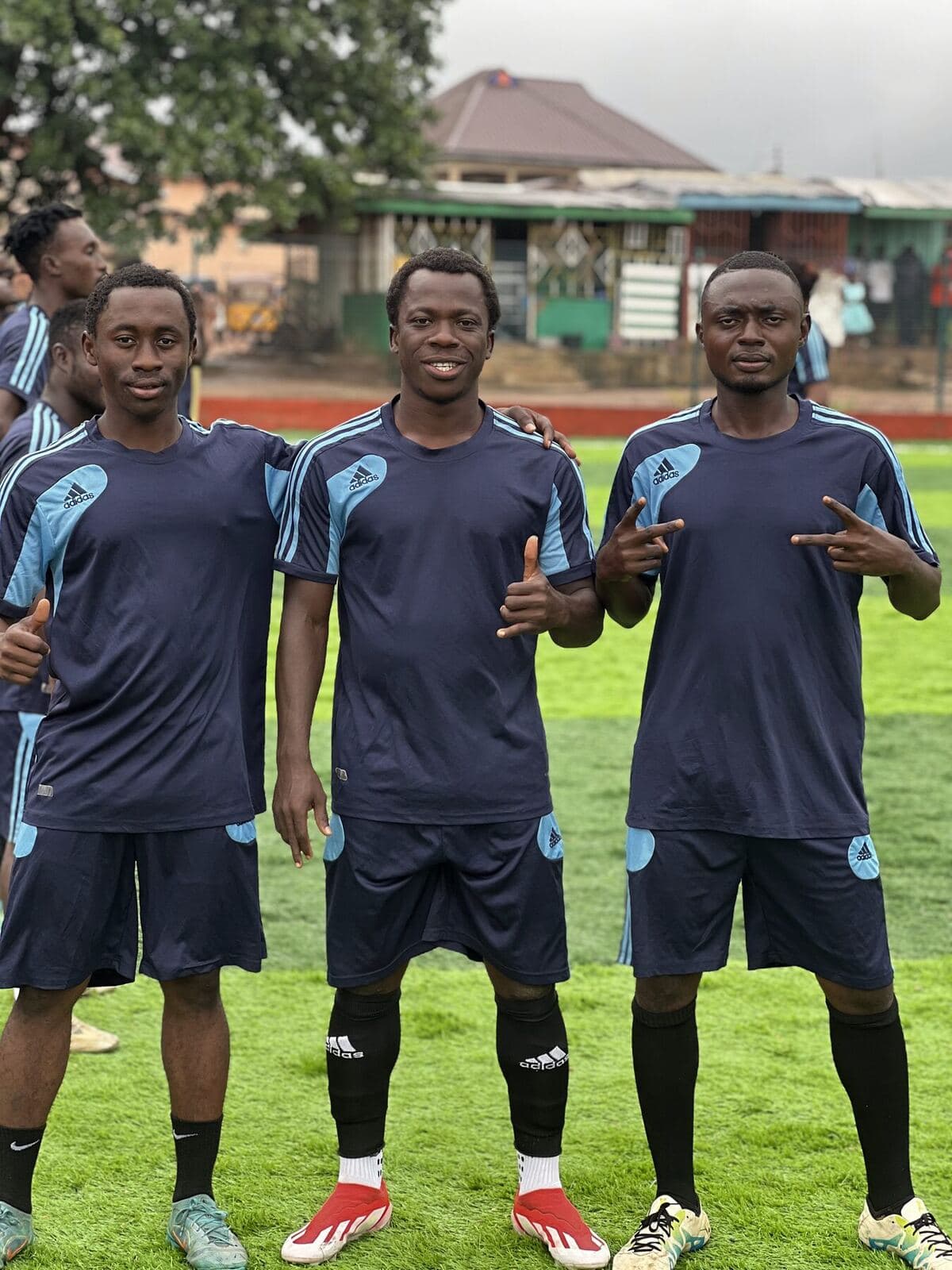 Three players in navy posing on the pitch