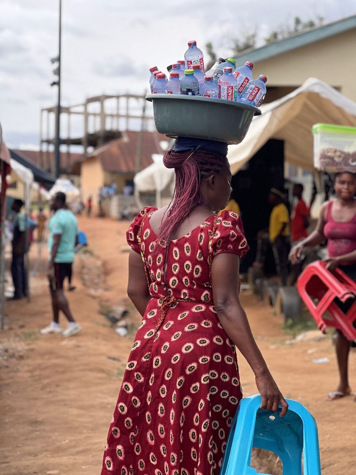 Woman carrying water to sell along the pitch