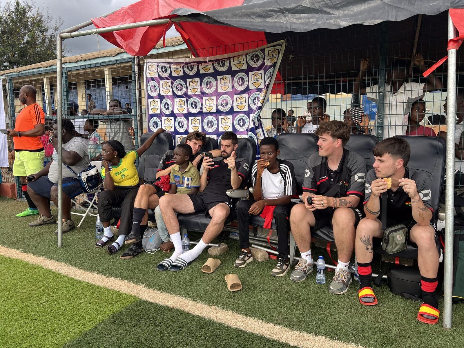 Supporters and players in the shade of the stand