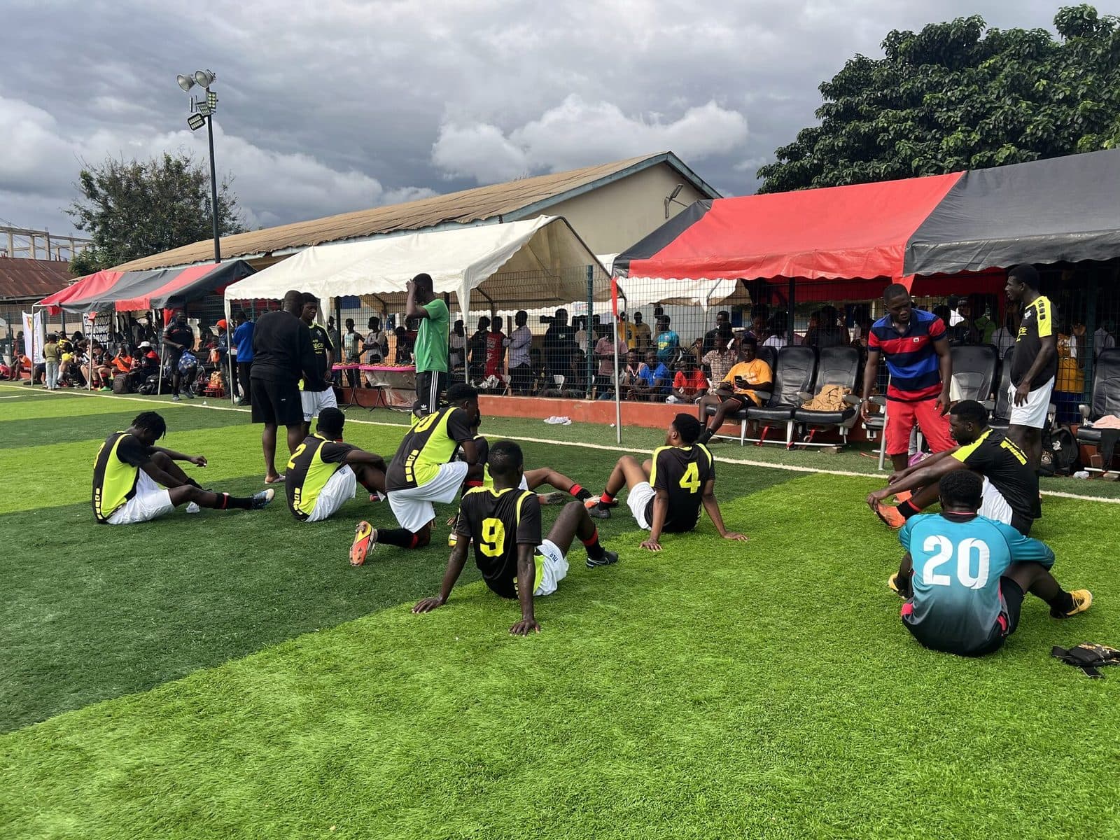 Team resting on the pitch in front of the stand